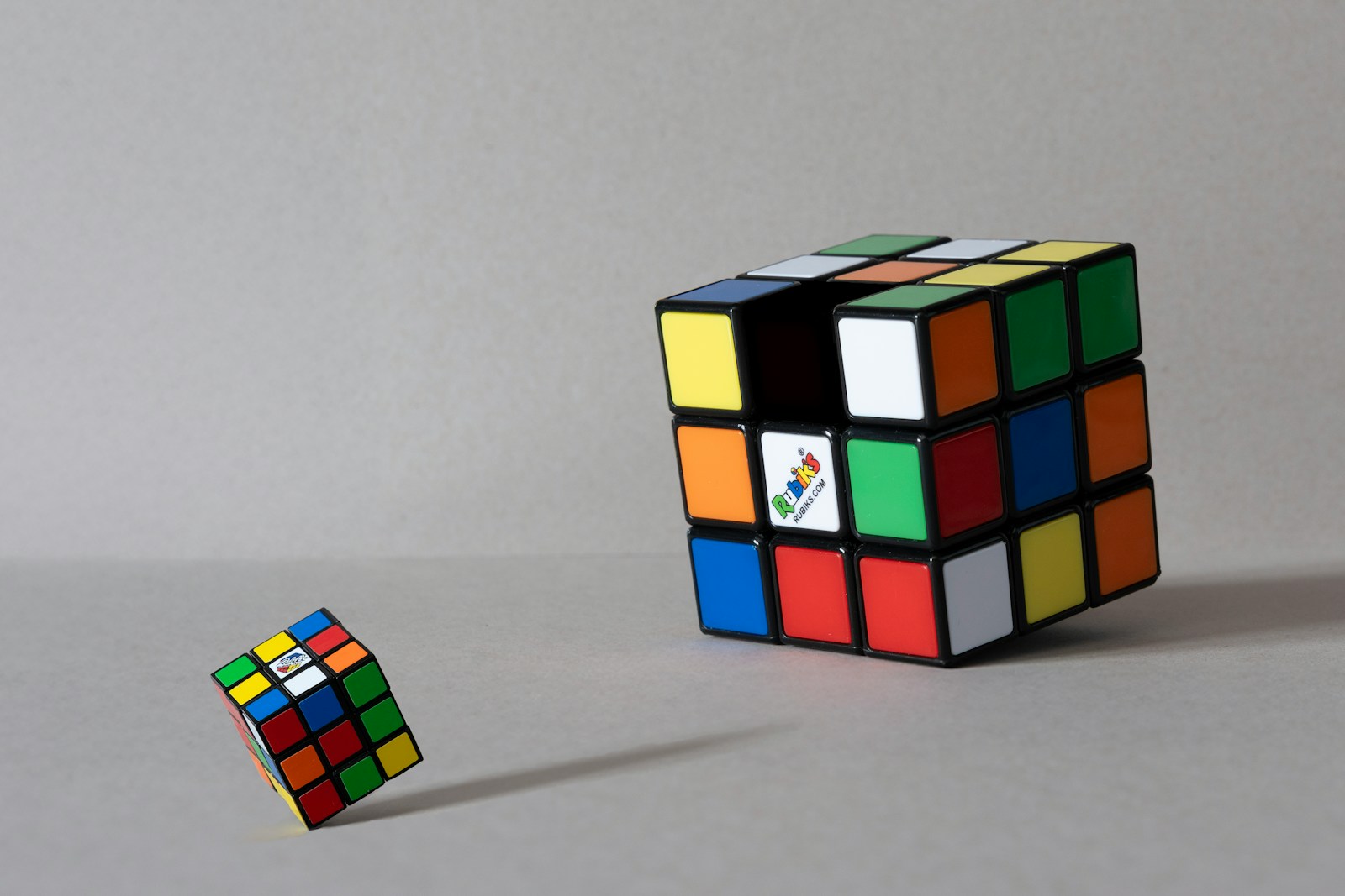 Two rubik's cubes on a gray surface