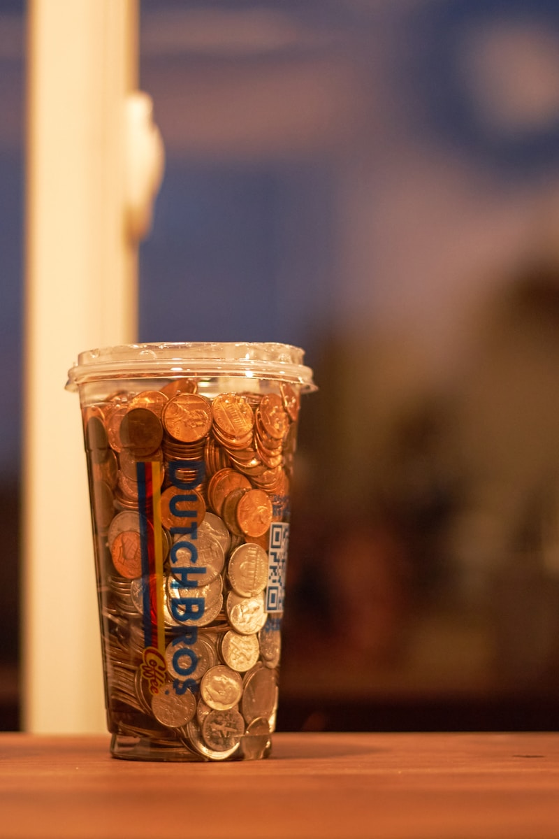 A cup filled with coins sitting on top of a wooden table